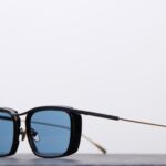 Lunettes de soleil Masunaga classique, monture en acétate noir avec branches en titane dorées.